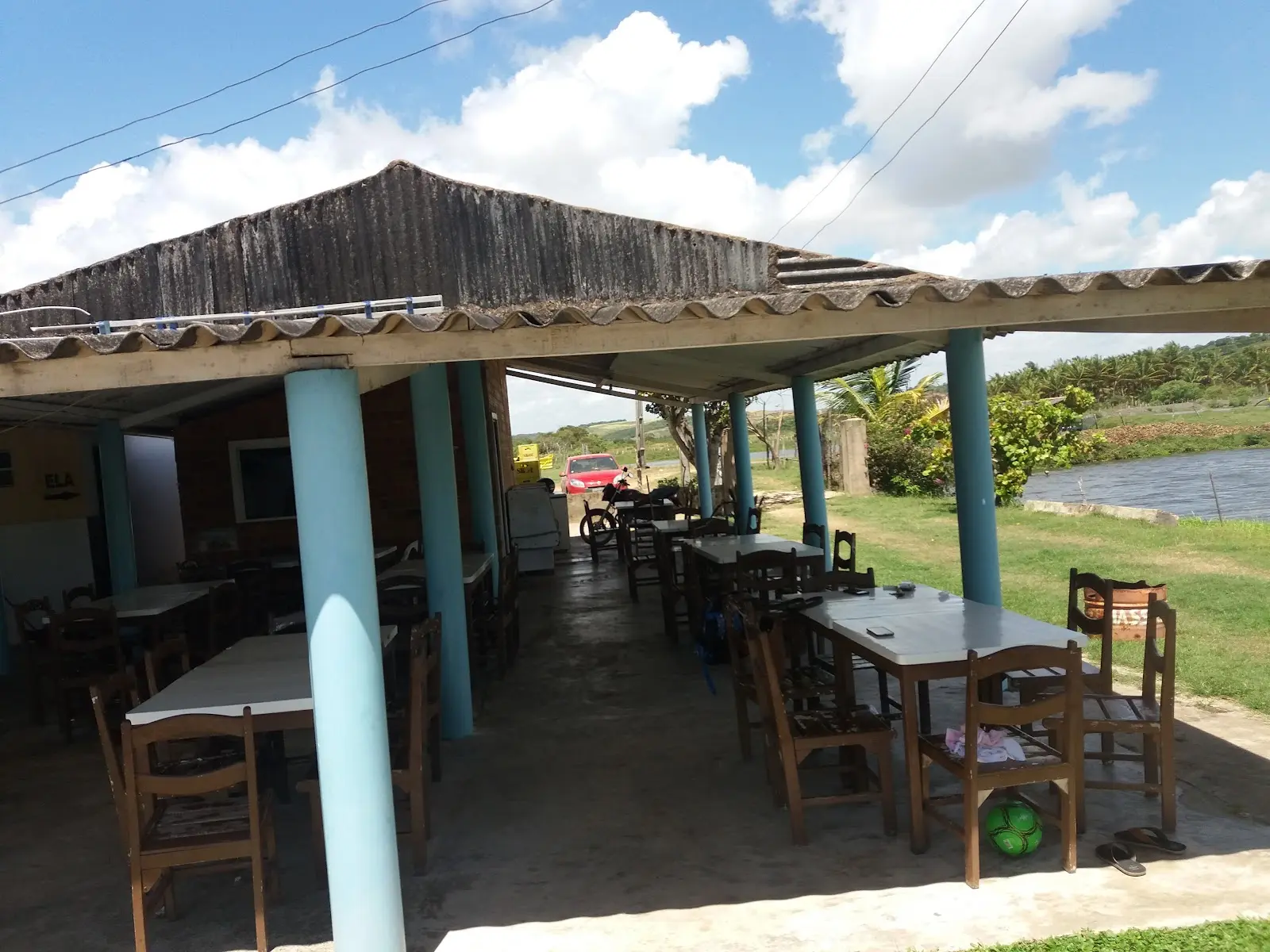 Restaurante coberto do Pesque Pague Massangana, com mesas de madeira e o lago ao lado