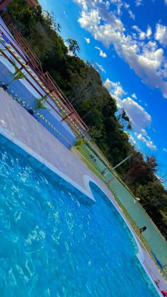 Piscina da Fazendinha Pesque & Pague com mata e céu azul ao fundo