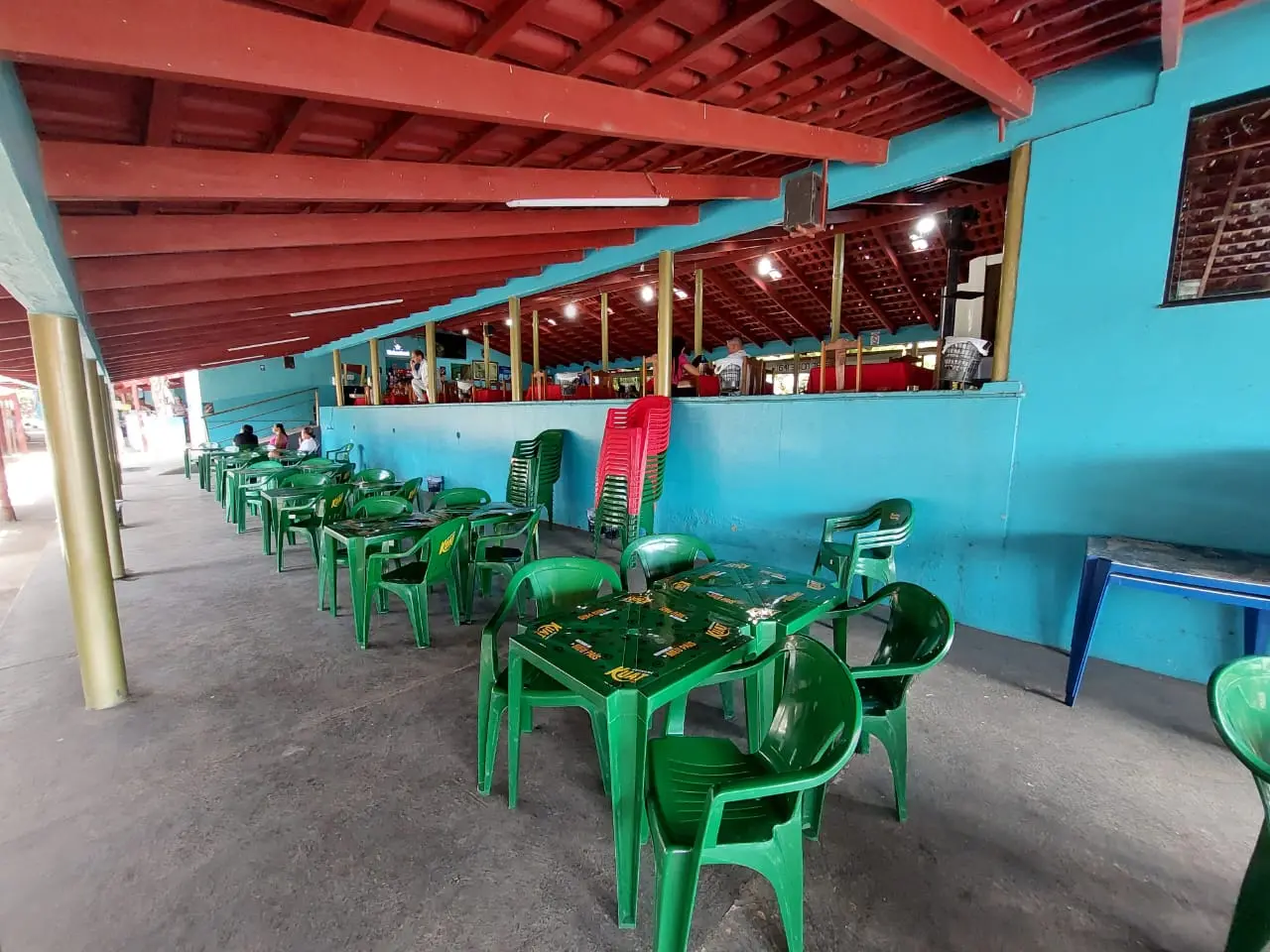 Salão coberto com mesas verdes do Pesque e Pague Pantanal, em São Luís de Montes Belos