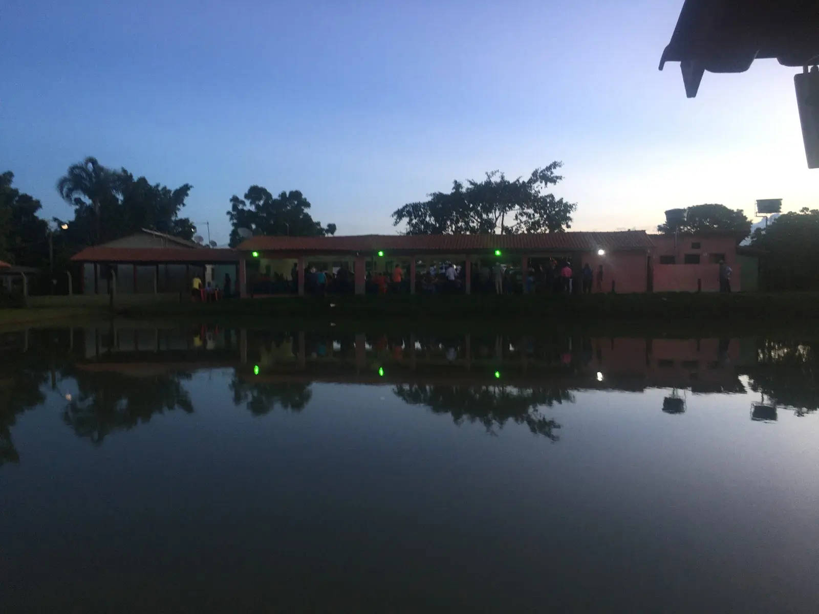 Tanque do Pesque-pague Andrade ao entardecer, com a área coberta iluminada ao fundo