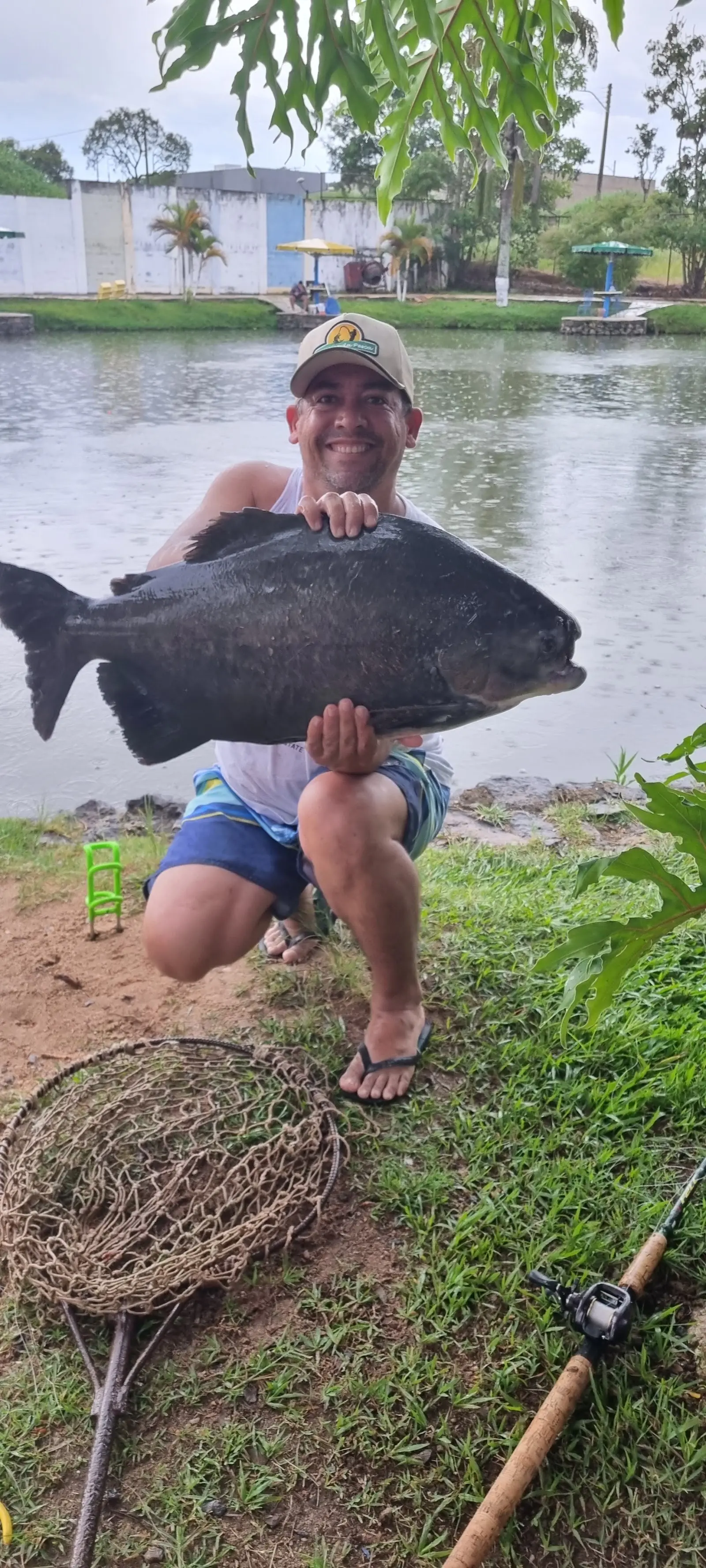 Pescador segura um peixe redondo grande na beira do lago do Clube de Pesca Lírios do Campo