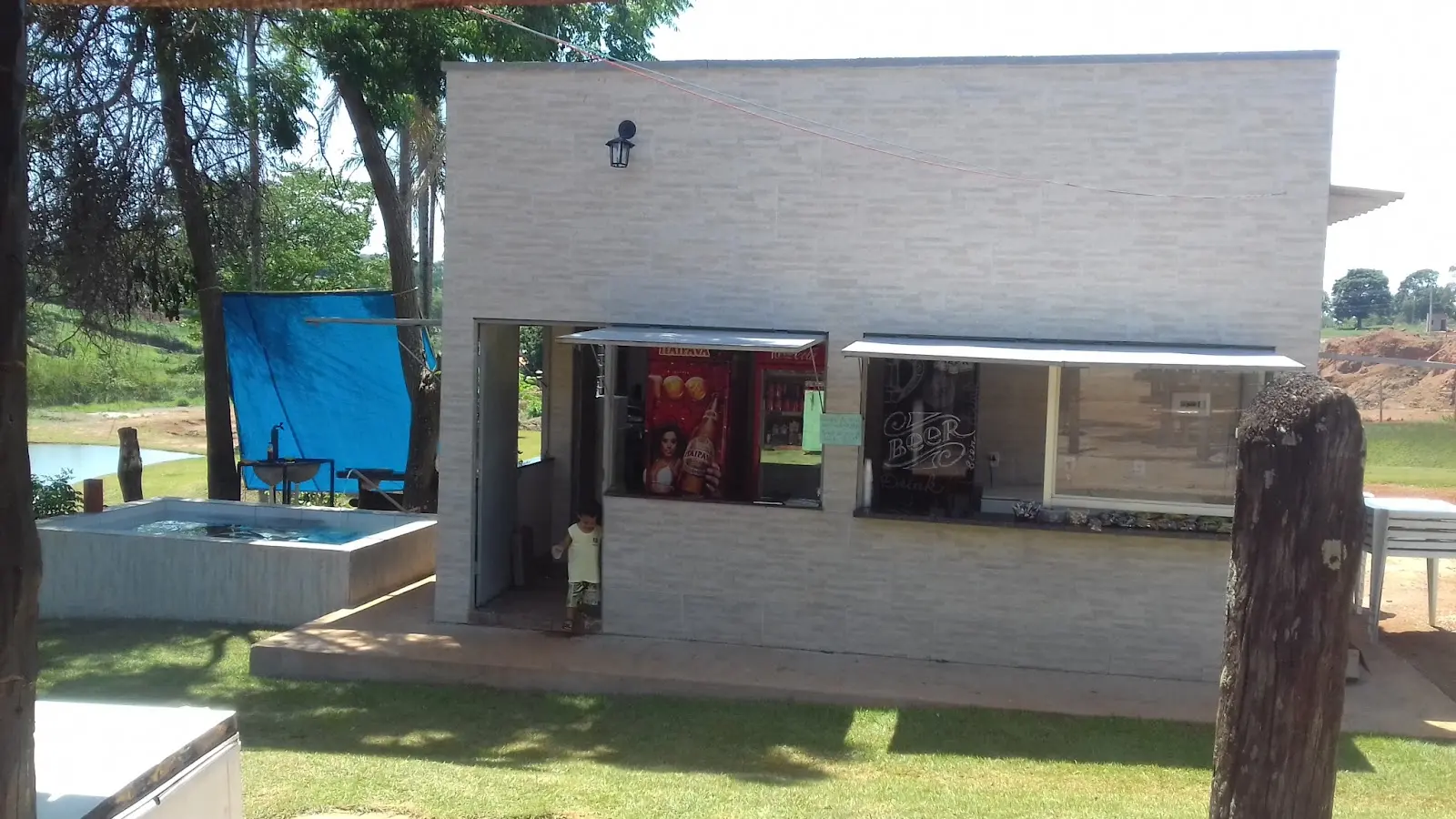 Construção da lanchonete do Clube de Pesca Paraíso, com gramado em volta e um pedaço do lago ao fundo