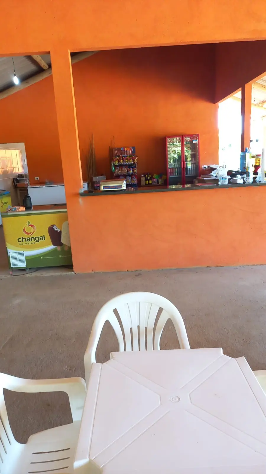 Balcão da lanchonete do Pesque e Pague Duas Irmãs, com mesa e cadeiras brancas na frente