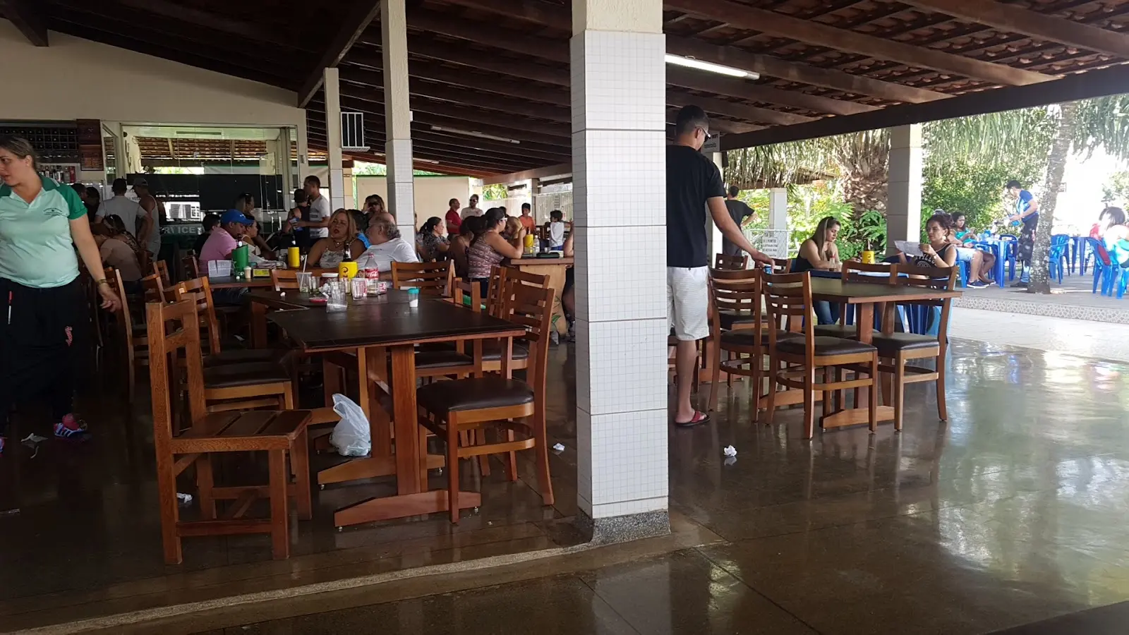 Salão coberto do restaurante do Pesque e Pague Esmeralda, com mesas de madeira e clientes almoçando