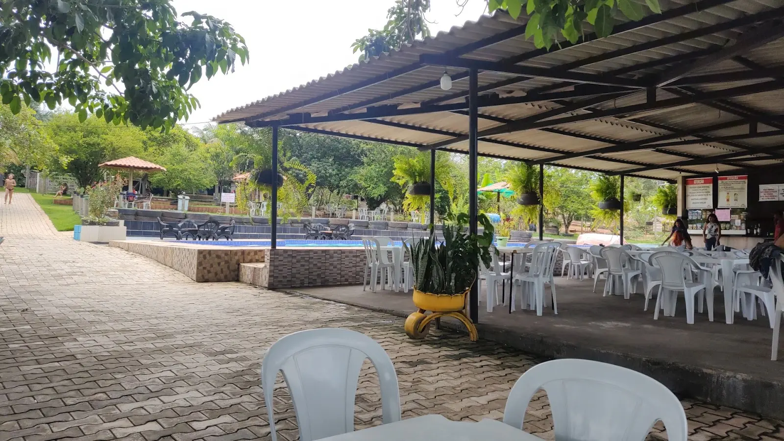 Área do restaurante com mesas cobertas e piscina ao lado no Pesque Pague Paraíba, em Trindade