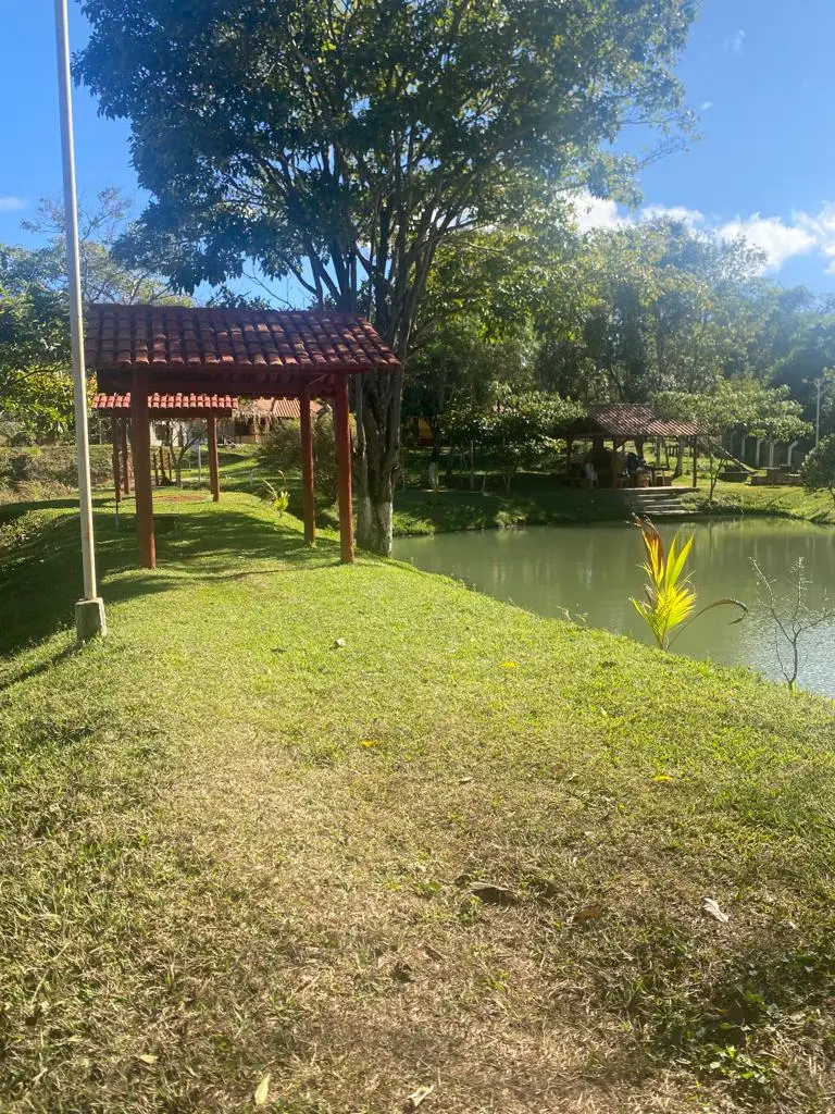 Gramado com quiosques de telhado de cerâmica ao lado do lago no Pesque Pague Recanto Faria