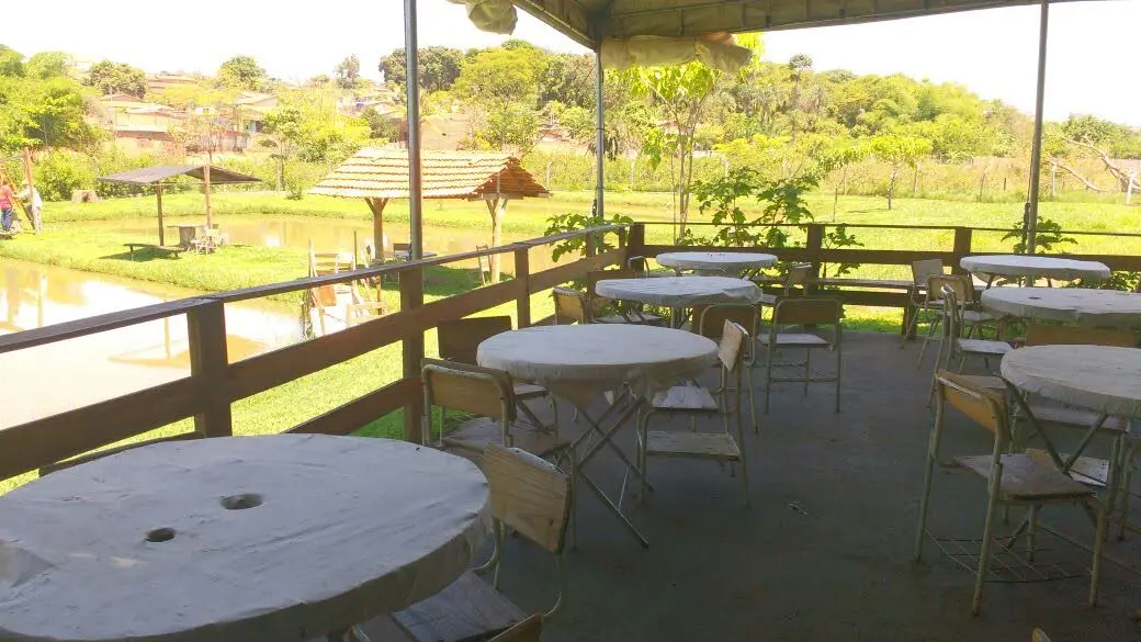 Área coberta com mesas de frente para o lago do Pesque Pague Recanto Imperial, em Trindade