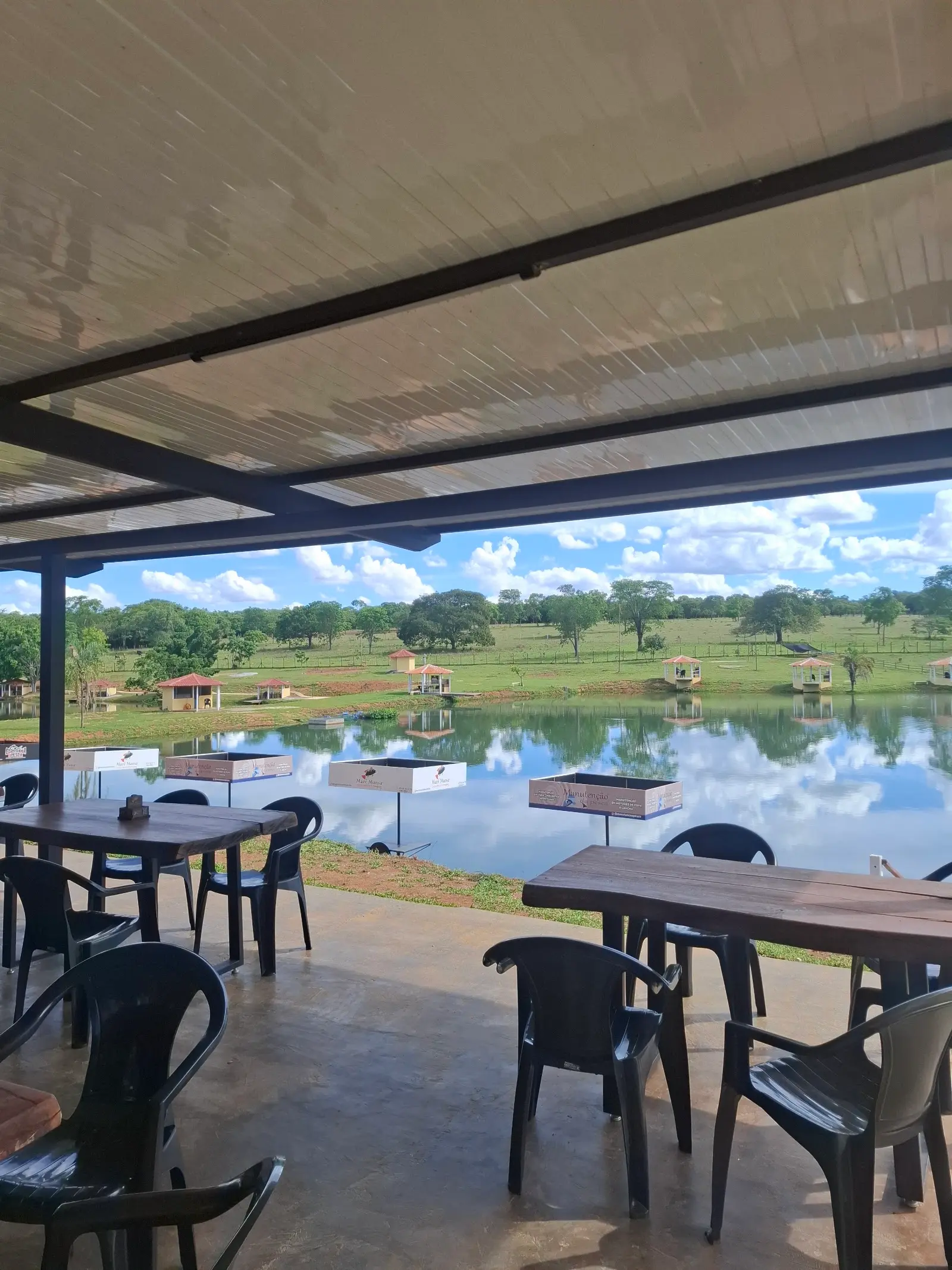 Lago com quiosques na margem visto da área coberta do restaurante do Vale do Dourado
