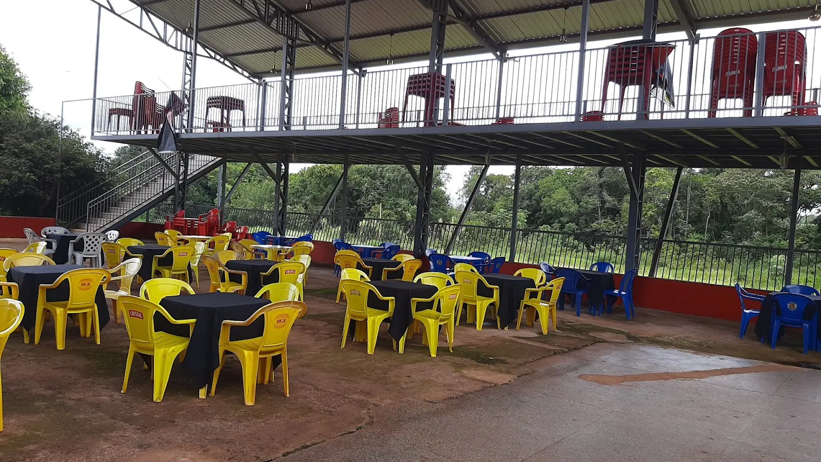 Área coberta com mesas e cadeiras plásticas e um mezanino com mais mesas no Pesque Pague e Eventos Mangueira