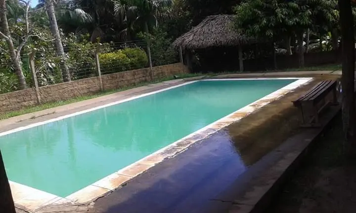 Piscina de água verde-clara com quiosque de palha e bancos de madeira ao fundo, no Pesque e Pague de Coroatá