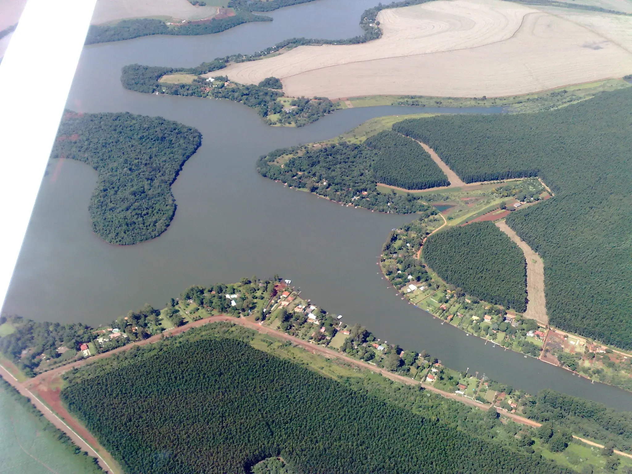 Vista aérea do lago da usina Mourão, com braços de água entre lavouras e mata