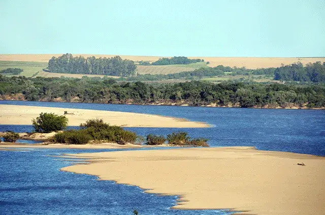 Águas largas do Rio Ibicuí correndo entre barrancos de mata na fronteira oeste gaúcha
