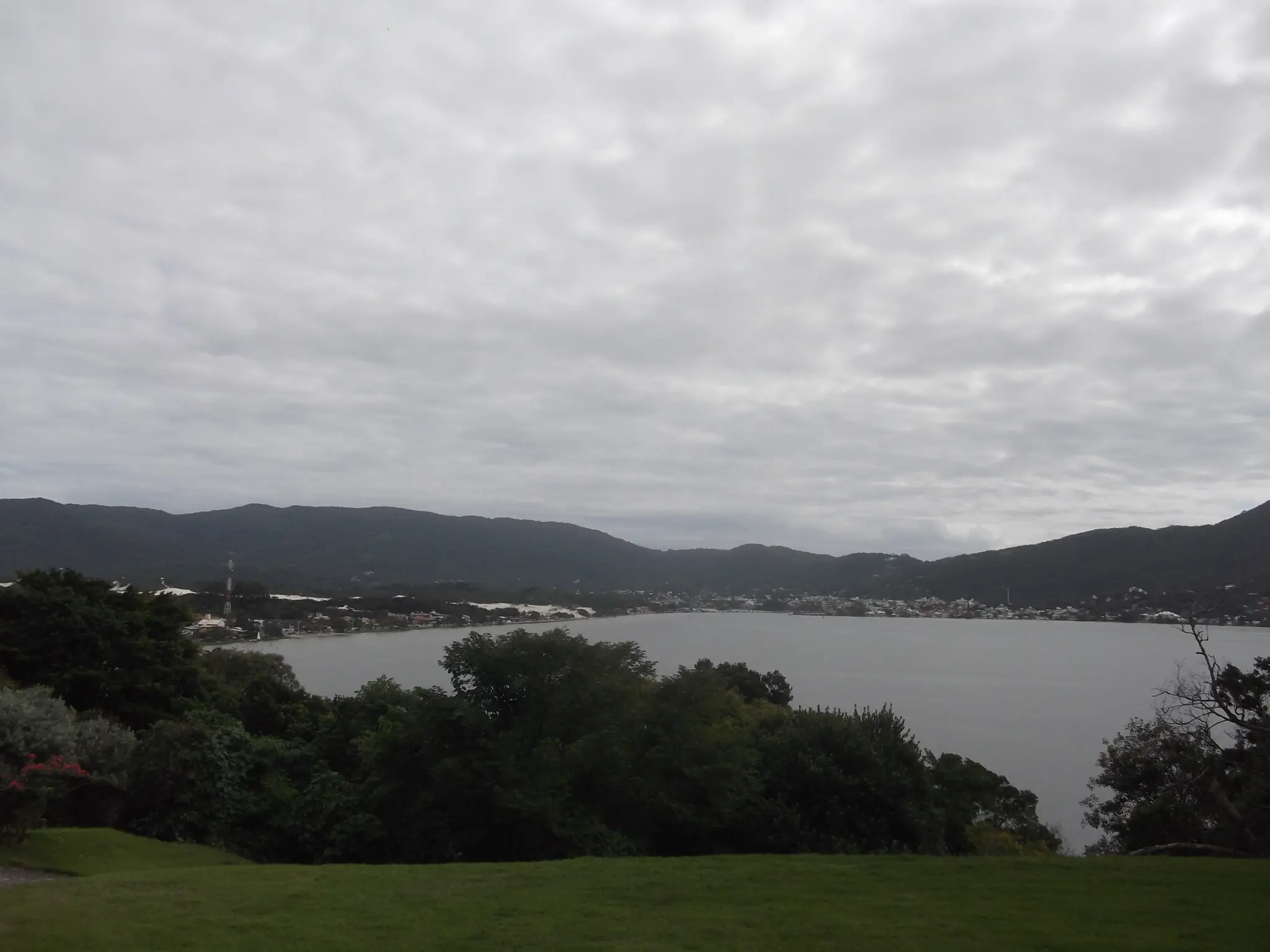 Vista da Lagoa da Conceição, com os morros ao redor e casas na beira da água