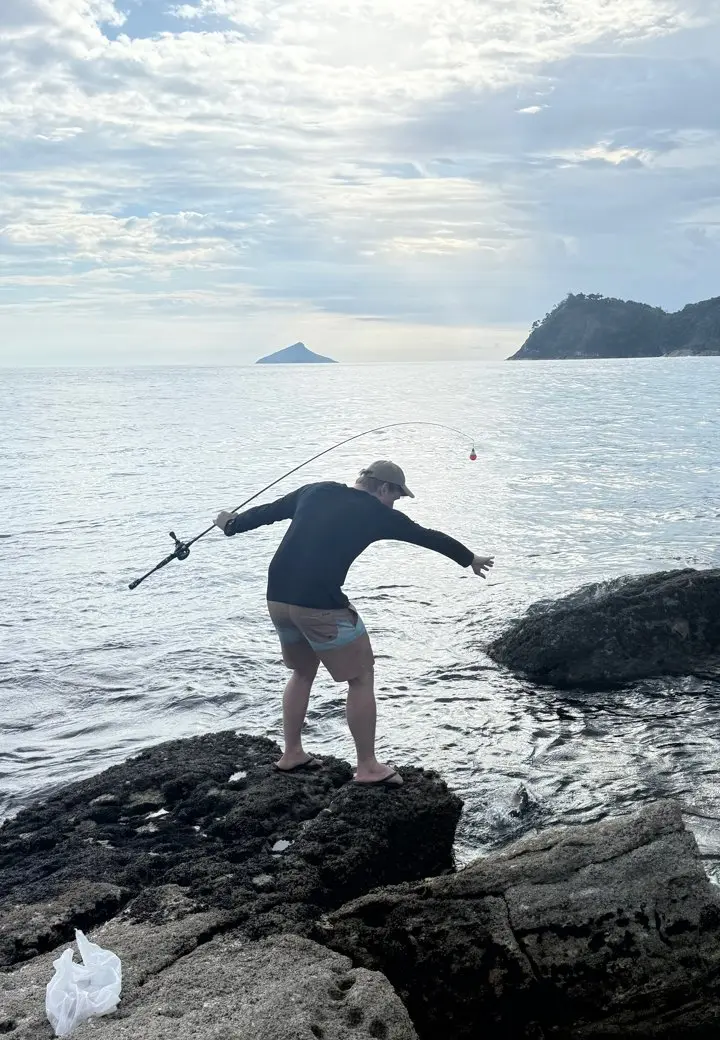 Pescador arremessando de cima da pedra