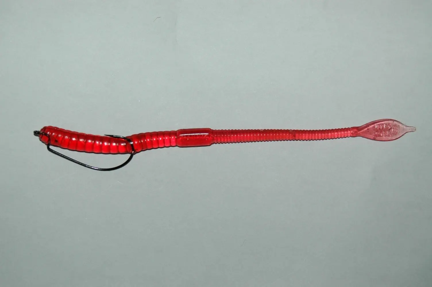 Minhoca de silicone vermelha presa em anzol offset, sem chumbo, sobre fundo cinza