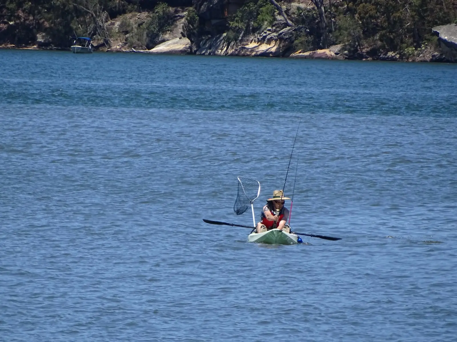 Pescador em caiaque sobre águas calmas com varas montadas