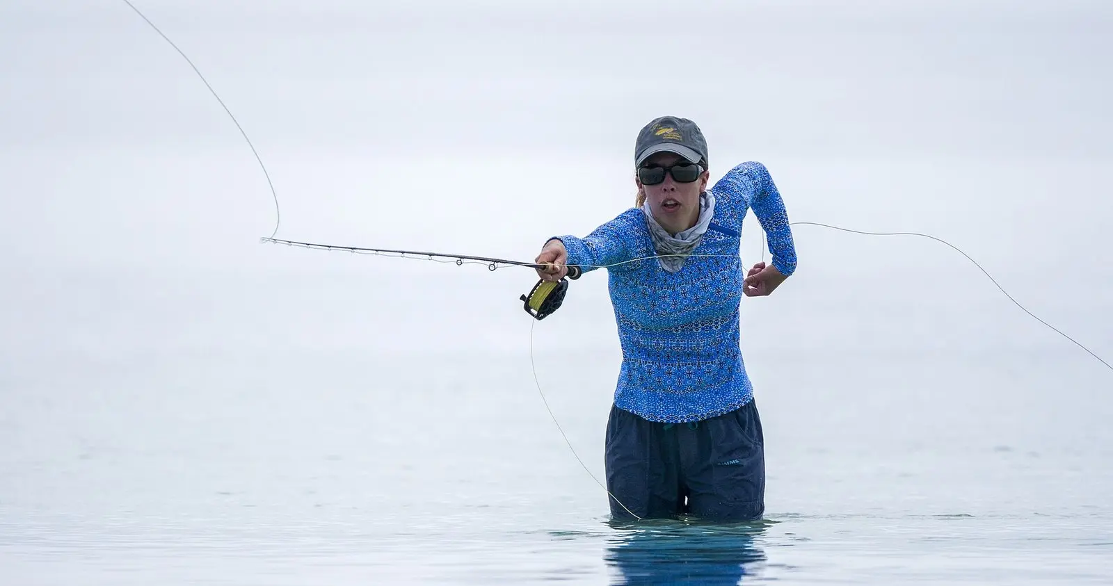 Pescadora com água na cintura arremessando com vara de fly nos baixios de mar nas Florida Keys