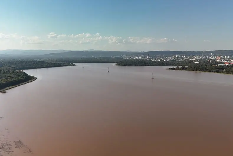 Lago com água turva visto da margem